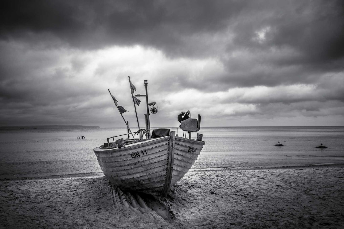 Ruderboot "BIN 11" am Strand in Binz auf der Insel Rügen in schwarz-weiß bei stark bewölktem Wetter (Schwarz-Weiß Fotografie)