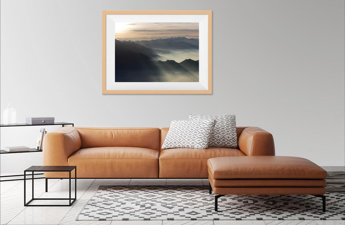 Foto di salotto con divano in pelle e stampa fine art con alba sulle montagne vista dalla Grigna