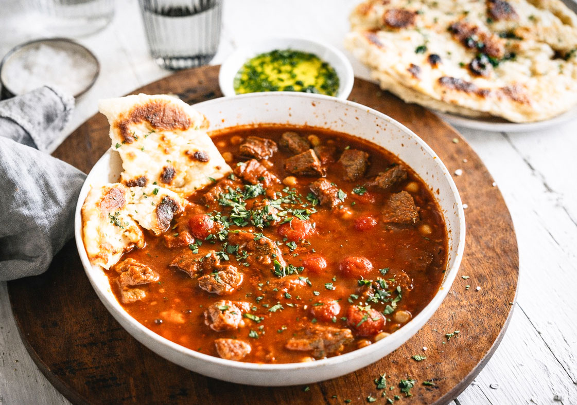 Orientalisches Rindergulasch in einem Teller mit Naan Brot serviert