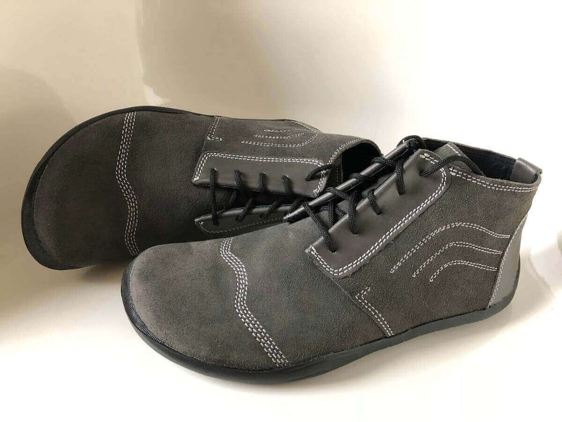 Knöchelhohe Barfußschuhe Modell Stone komplett aus Veloursleder in grauer Farbe mit weißen Nähten, schwarzen Senkeln und einer schwarzen Laufsohle