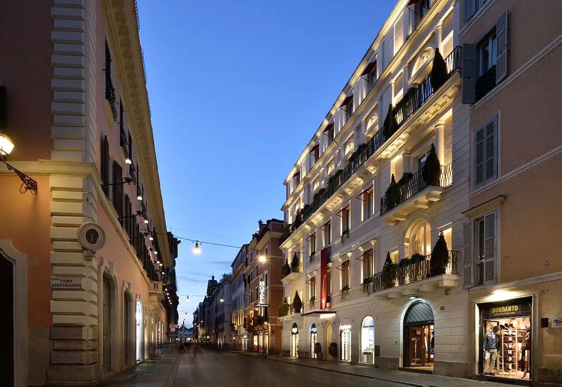 Ansicht des dezent beleuchteten First Dolce Hotels an der Via del Corso im letztem Tageslicht eingefangen