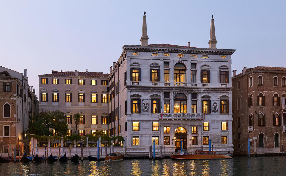 Das Aman Venice Hotel in abendlicher Stimmung mit erleuchteten Fenstern im letzten Tageslicht vom Canal Grande aus