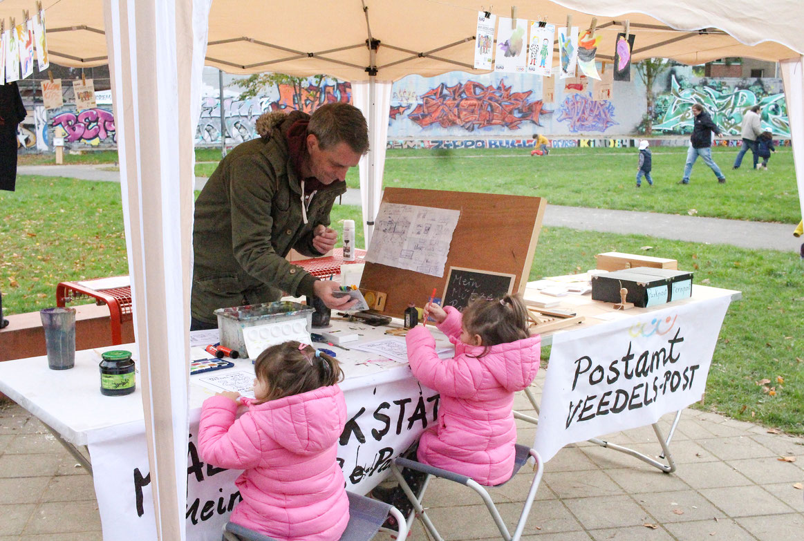 Malwerkstatt des STARKE VEEDEL BÜROs. Kinder malen auf vorgedruckten Postkarten. Im Postamt erhalten die Kinder Briefmarken und Stempel. Der Veedels-Briefkasten wird am Ende entleert. Ein T-Shirt wurde unter den jungen Künstler*innen verlost.