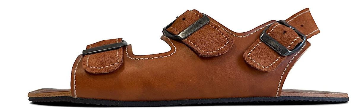 Handgefertigte Sandale Jet aus braunem Leder mit weißen Nähten. Drei Riemen verstellbar mit Schnallen aus Metall. Laufsohle 3 mm Kautschuk in Schwarz.