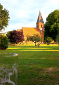 Eine Dorfkirche mit Bierglas im Vordergrund