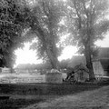 Hof Ganzow -  um 1920 | Blick vom Gutshaus zur Weizen- und Gerstenscheune, mittig: der mit Findlingen befestigte Teich, im Vordergrund: Holzmiete und landwirtschaftliches Gerät