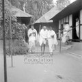 Mahatma Gandhi and others walking on an ashram compound during his peace march in Noakhali, c. November 1946.