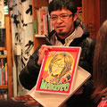 似顔絵工房ニコットの道工真理（どうこうまり）さんより贈られた石井さんの似顔絵ウェルカムボード。そっくり！　プレセンターは主催者の吉田さん。