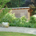 Wildhecke als Hofbegrenzung, dahinter ein neues Müllhaus