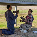 2022 07 13 Darren Gephart & his son Dylan are hard at work getting the Uni Skeet traps mounted  on Ground 2. Sally, their 17 year old pup, is supervising the job, so it should be all OK.