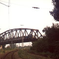 Nahverkehrszug fährt über Eisenbahnbrücke an Stellwerk Swo.
