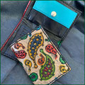 Kleiner Ledergeldbeutel mit Punzierung Paisley, bunt; dahinter Innenansicht kleiner Geldbeutel, Ziegenleder in verschiedenen Blautönen.
