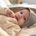 Baby mit Erstlingsmütze liegend
