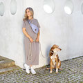Frau und Hund wartend an einer Hausecke