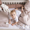 Baby im Kinderbett mit Bettwäsche von Träumeland