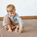 Kind hockend spielend mit Holz-Spielzeug
