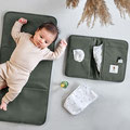 Baby auf Wickelunterlage neben Windel & Windeltasche