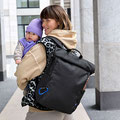 Mama trägt Baby auf dem Arm und Wickelrucksack von LÄSSIG über der Schulter