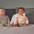 Zwei fröhliche Babys sitzend auf einer Couch