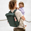 Papa mit umgehängten Wickelrucksack von LÄSSIG trägt Baby auf dem Arm