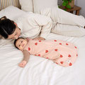 Mutter mit Baby schmusend im Elternbett