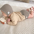 Baby mit Erstlingsmütze auf dem Bauch liegend