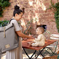 Mama mit Rolltop und Babysitzend auf einem Tisch