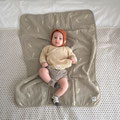 Baby mit Muslin-Kleidung liegend auf einer Krabbeldecke