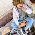 Junge knabbert gesunden Snack aus der Bambus-Brotdose von LÄSSIG