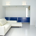光沢のある床タイルに青い居間家具が映えるリビング