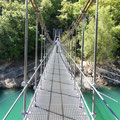 Eine Hängebrücke führt über das türkiesfarbene Wasser.
