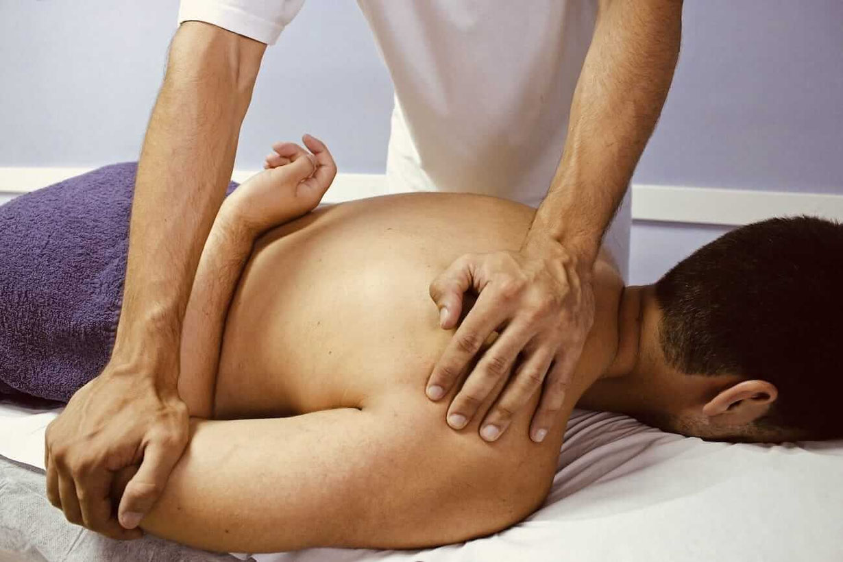 Faszien-Therapeut arbeitet mit den Händen an Schulter