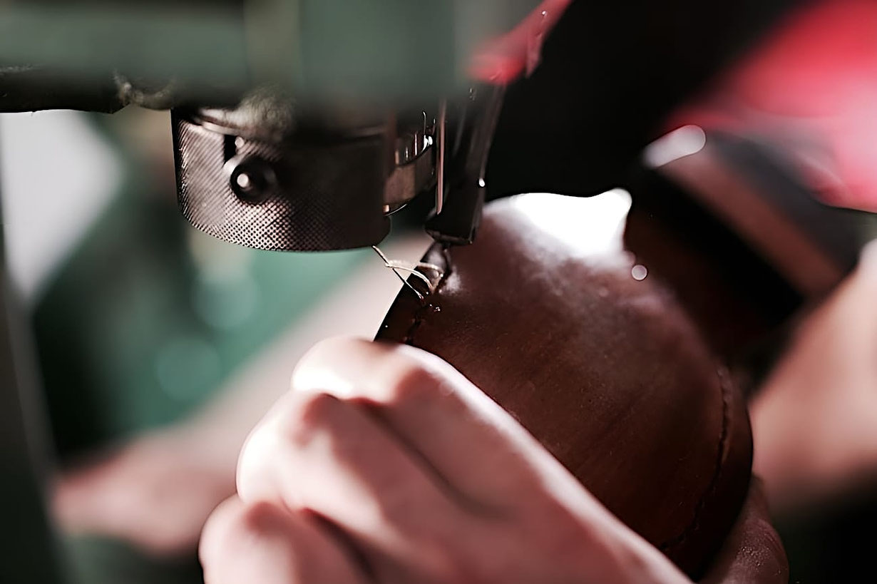 An der Nähmaschine wird ein Barfußschuh aus Leder genäht