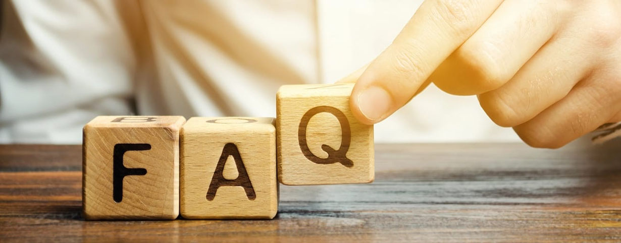 Drei Holzwürfel mit jeweils einem Buchstaben F-A-Q liegen auf einem Tisch