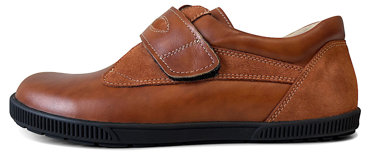 Barfußschuh aus braunem Leder mit einem breiten Klettverschluss aus braunem Leder und stark profilierter schwarzer Sohle.