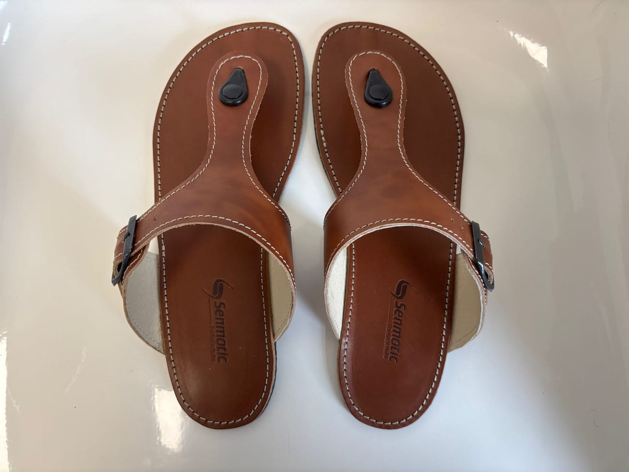 Handgefertigte Flip-Flops aus Deutschland. Aus braunem pflanzlich gegerbten Rindsleder und einem beigen Innenfutter. Mit einer Schnalle aus Metall zum Verstellen.