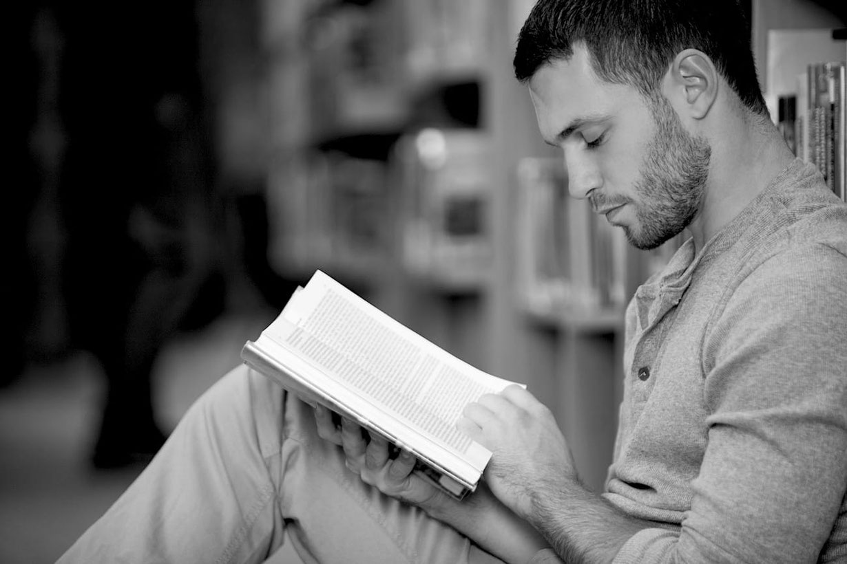 Junger Mann sitzt in Stuhl und liest ein Buch über Senmotic