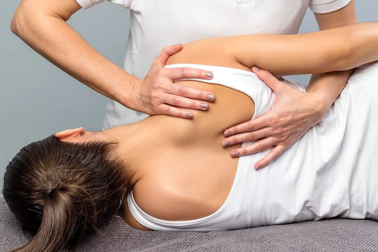 Faszien Therapeutin arbeite mit den Händen am Rücken einer Patientin