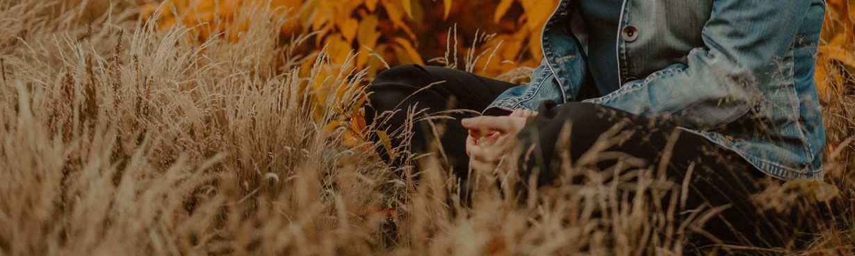 Hände im Schoß in ruhiger Natur – ein Moment der inneren Rückverbindung und Selbstwahrnehmung.