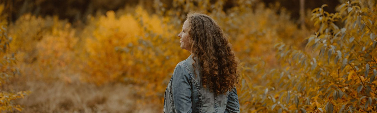 Susanne Kruse steht ruhig in herbstlicher Natur, mit weichem Blick zur Seite. Ein Moment von Klarheit und innerem Ankommen.