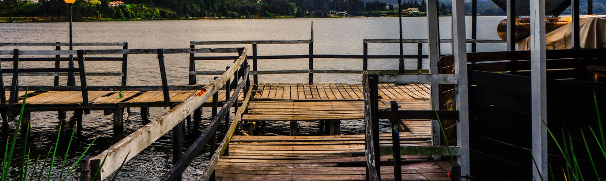 Alter Holzsteg am See, der ruhig trägt und einen offenen Raum über dem Wasser bildet.
