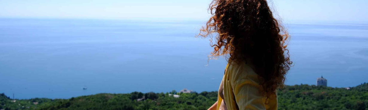 Frau mit Blick über weite Landschaft und Meer – Symbol für Lebensweg, Entscheidungen und spirituellen Weg