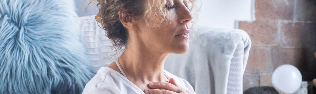 Frau sitzt still mit den Händen auf dem Herzen – ein Moment innerer Führung, Klarheit und Bewusstsein.