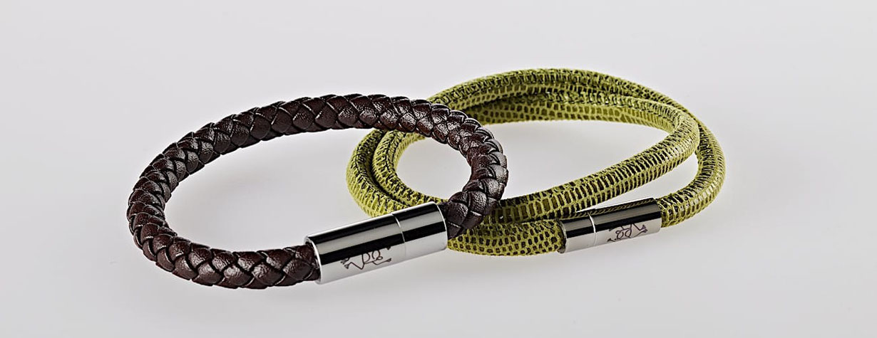 _Ein Lederarmband Farbe Braun mit Magnetverschluss in der Front liegt auf einem doppelten Lederarmband Farbe Grün mit Magnetverschluss in der Front