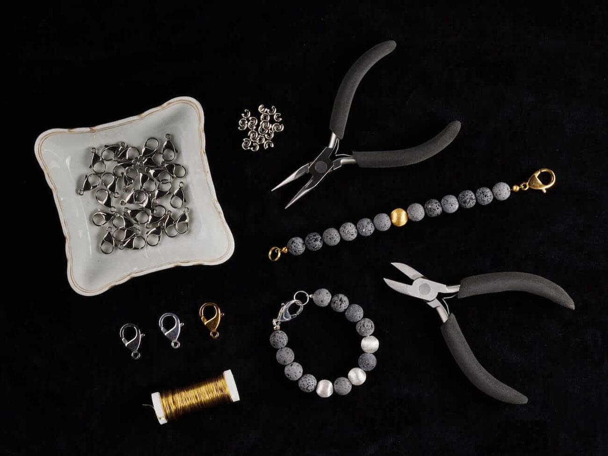 Aus der Vogelperspektive die einzelnen Bestandteile der Perlenarmbänder aufgereiht bis hin zum fertigen Armband.