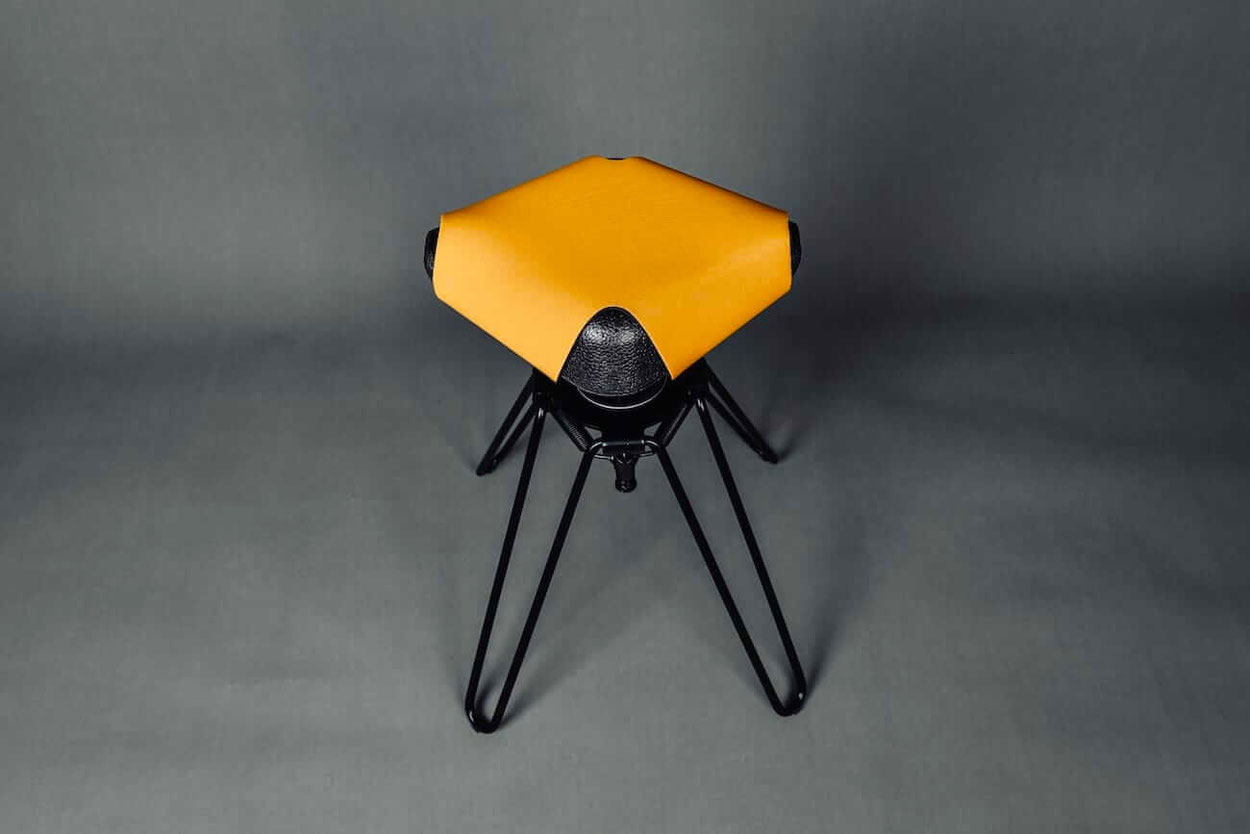 Schwarze Sitzschale eines Pendelhockers mit einem orangen Sitzpolster