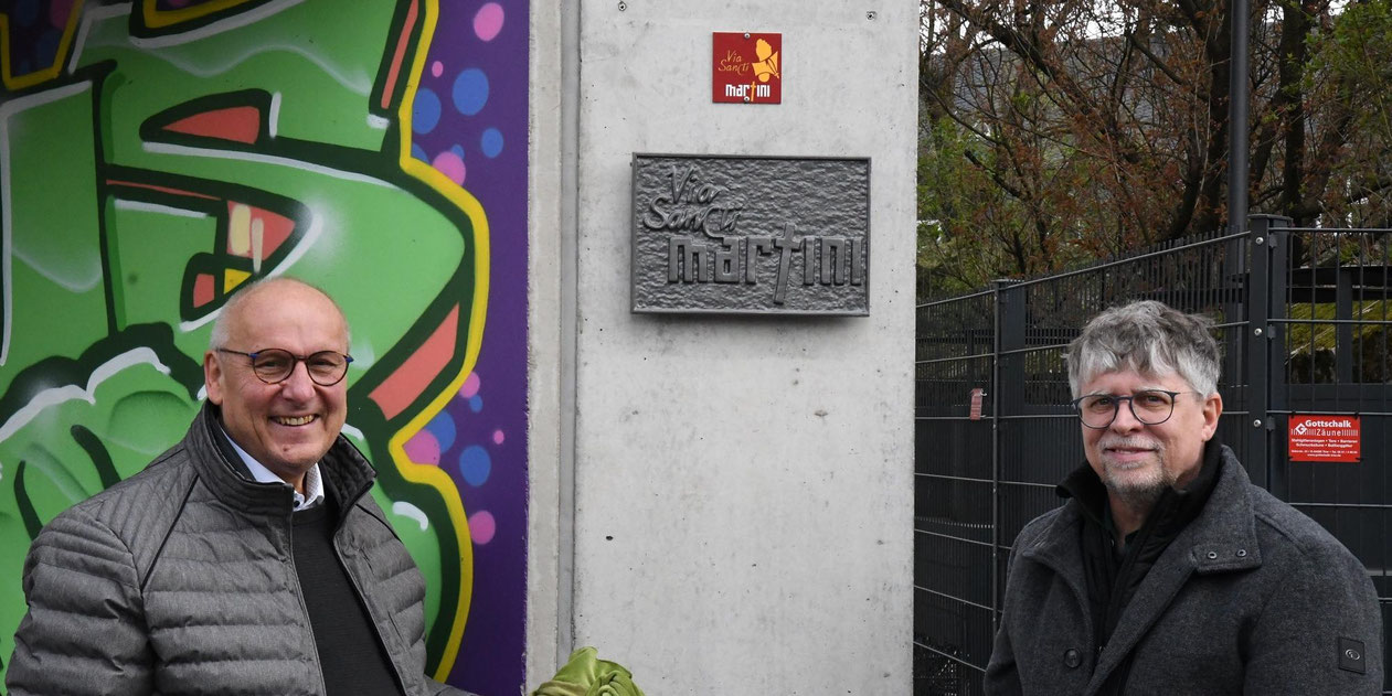 Horst Drach (links) und Andreas Wagner präsentieren die frisch enthüllte Wegmarke und die Plakette zum Martinusweg. Foto: © Luca Peranni