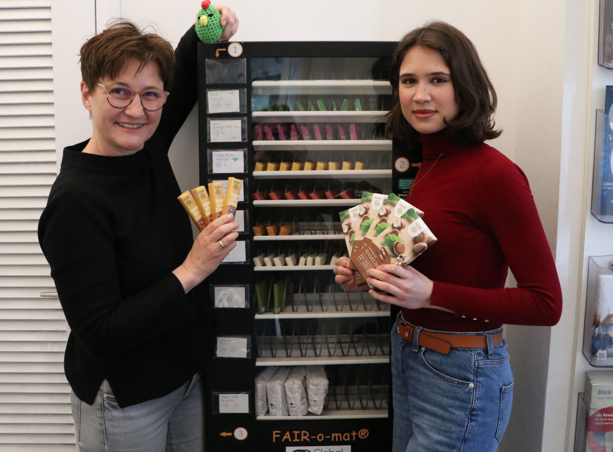 Andrea Aippersbach und Julia Mittermeier mit dem Grünen Hahn vor dem „Fair-o-Maten“ Bildquelle: Universität Hohenheim / Billmaier 