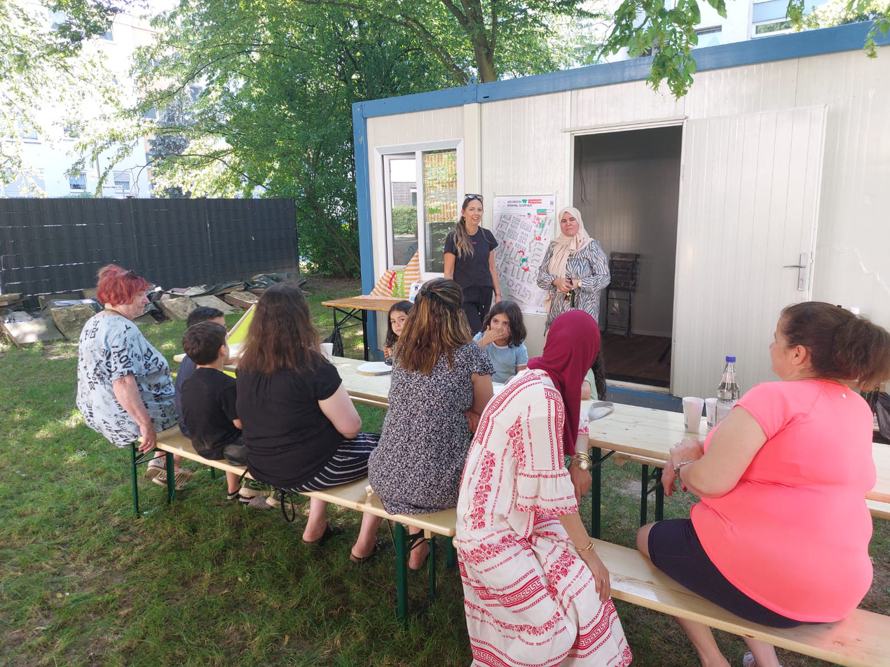 Nachbar*innen diskutieren in der Hallo Nachbar Oase am Ludwig-Quidde-Platz in Neubrück.