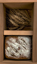 Foto von der Brotbackform von oben, in dem unteren Fach ein gebackenes Brot, im oberen Fach Weizen